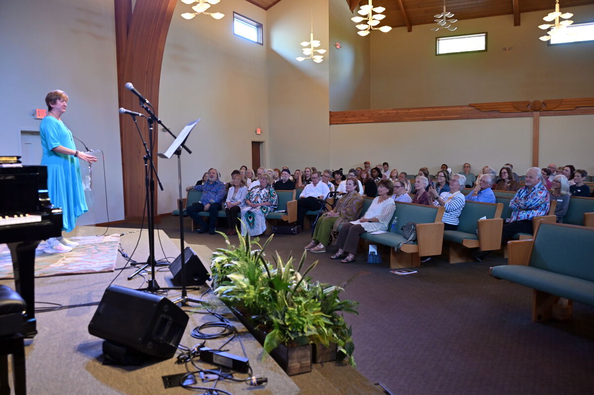 The sanctuary on Homecoming Sunday seen from the platform side, Rev. Robin Reiter speaking and the pews full