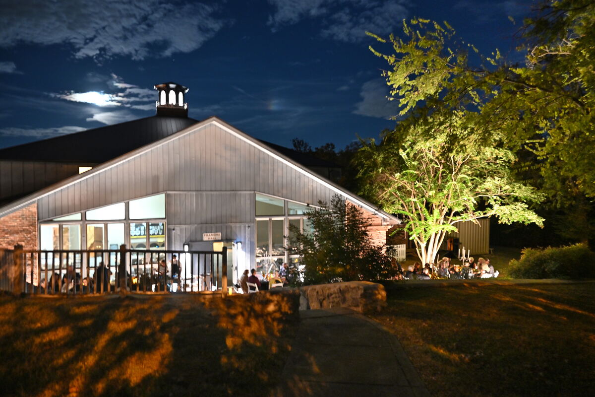 The church at night, lit from below, the moon above the roofline and the last of the guests on the patio