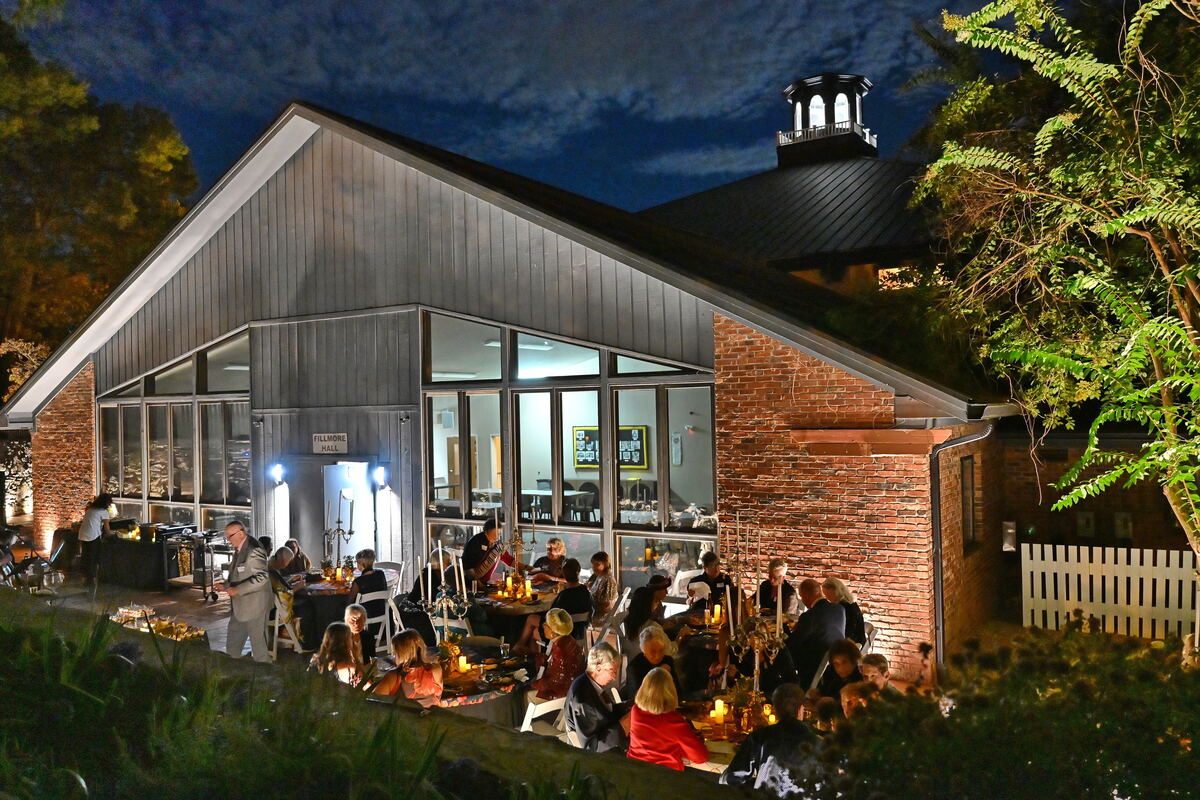 The church at dusk on the evening of the Gala, guests gathered on the lit patio beneath a deep blue sky